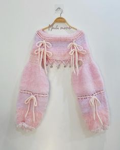 a pink and white sweater hanging on a hanger