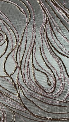 an abstract pattern made with metallic thread and sequins on a gray fabric background