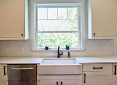 a kitchen with white cabinets and stainless steel dishwasher in front of a window