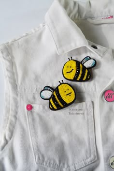 two yellow and black bees are on the back of a white shirt with pink buttons