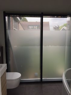 a bathroom with sliding glass doors leading to a bathtub and toilet in the corner