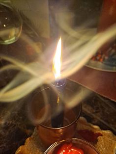 a candle that is sitting in some kind of bowl with food on the table next to it