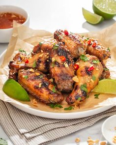 chicken wings with lime wedges and sauce on the side, ready to be eaten