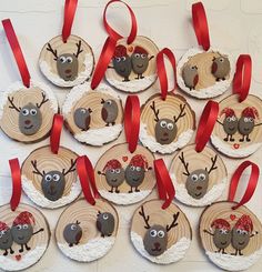 christmas ornaments made from wood slices with reindeer faces and red bows on them, hanging on a white wall