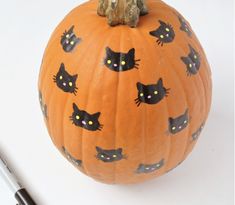 a pumpkin with black cats painted on it and a marker pen next to the pumpkin