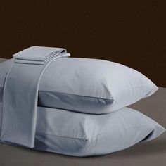 two white pillows are stacked on top of each other in front of a brown wall