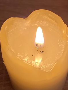 a lit candle in the shape of a heart