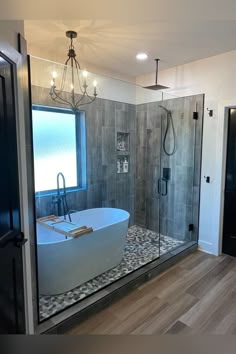 a bathroom with a large bathtub next to a walk in shower and a chandelier