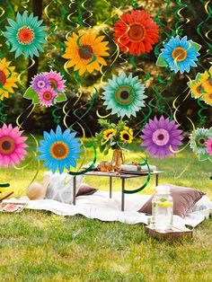 an outdoor party with sunflowers and streamers hanging from the ceiling, in front of a picnic table