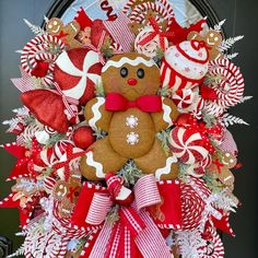 a christmas wreath with a gingerbread bear and candy canes on it, hanging from the front door