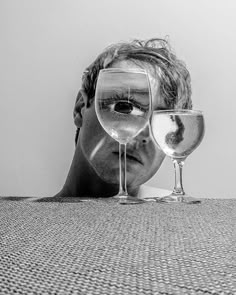 a man looking through two wine glasses on the floor in front of his face,