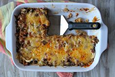 a casserole dish with cheese and meat in it next to a spatula