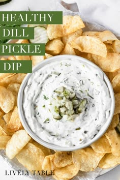 healthy dill pickle dip in a white bowl surrounded by tortilla chips