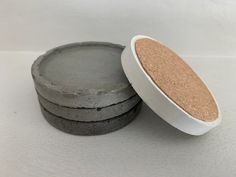 three round concrete coasters sitting next to each other on a white surface with a cork lid