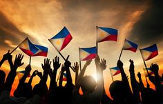 many people are holding flags and waving them in the air at sunset or sunrise time