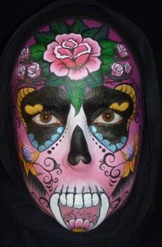 a woman with makeup painted to look like a skull and roses on her face, wearing a black hoodie