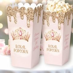 two pink popcorn boxes with gold glitter crowns on them, sitting next to each other