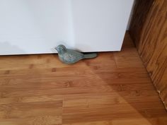 a small bird sitting on the floor next to a refrigerator