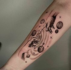 a person with a tattoo on their arm that has an image of a hand reaching for planets