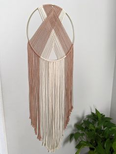 a macrame hanging on the wall next to a potted plant