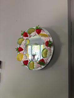 a mirror that has some fruit on it and is hanging on the side of a wall