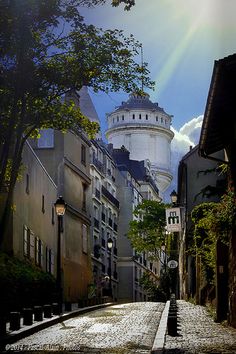 the sun shines brightly on an old street with cobblestone streets and buildings