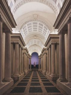 an empty hallway with columns and arches in the center is lit by a purple light