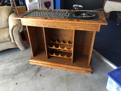 a wooden table with a record player and wine rack on it in a room filled with furniture