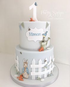 a three tiered cake with an animal theme on the top and bottom layer is for a first birthday