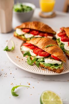 there are many sandwiches on the plate with lettuce and tomato slices next to each other