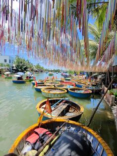 many small boats are tied to the shore by streamers and hanging from palm trees