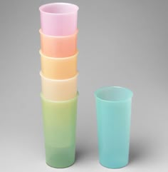 a stack of pastel colored cups sitting next to each other on a gray background