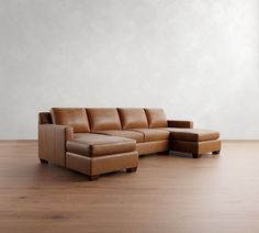 a brown leather couch sitting on top of a hard wood floor next to a white wall