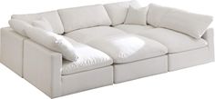 a large white couch with pillows on it's back end and arm rests against the wall