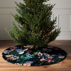 a small christmas tree is on the floor in front of a round mat with lights