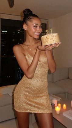 a woman in a gold dress holding a cake