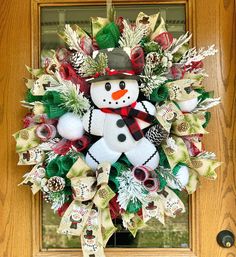 a christmas wreath with a snowman on it in front of a wooden door and window