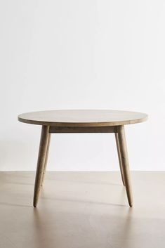 an oval table with wooden legs and a white wall in the background, against a plain backdrop