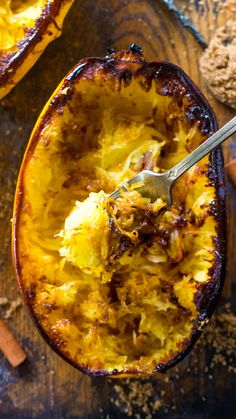 the inside of a baked delicacy dish with a spoon in it and cinnamon sticks on the side