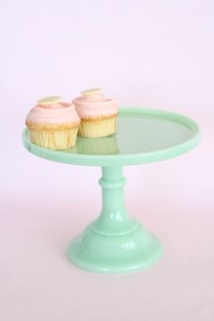 two cupcakes sitting on top of a green cake plate