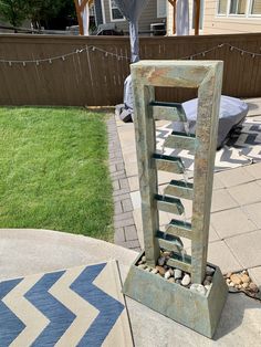 a metal sculpture sitting on top of a patio next to a green grass covered yard