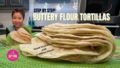 a stack of tortillas sitting on top of a green table cloth next to a woman