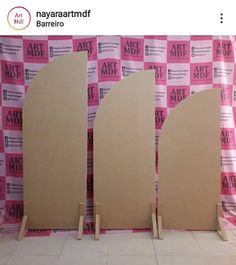 three wooden doors are standing in front of a pink backdrop