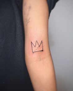 a small crown tattoo on the arm