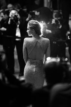 a black and white photo of a woman in a dress on the red carpet with cameras around her