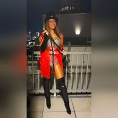 a woman dressed in red and black posing for the camera on a balcony at night