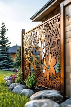 a wooden gate in the middle of some grass and rocks with flowers on it next to a house