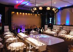 a banquet hall with tables and chairs set up for an event or function, lit by colorful lights