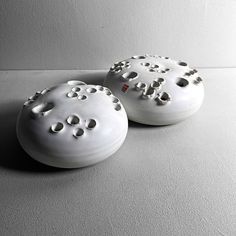 two white vases sitting on top of a table next to each other with holes in them