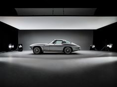 a black and white photo of a car in a dark room with spotlights on the floor